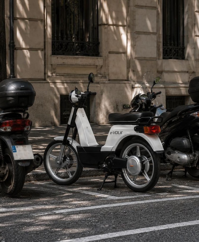 Moto eléctrica e-VOLK aparcada junto a otros vehículos en la ciudad